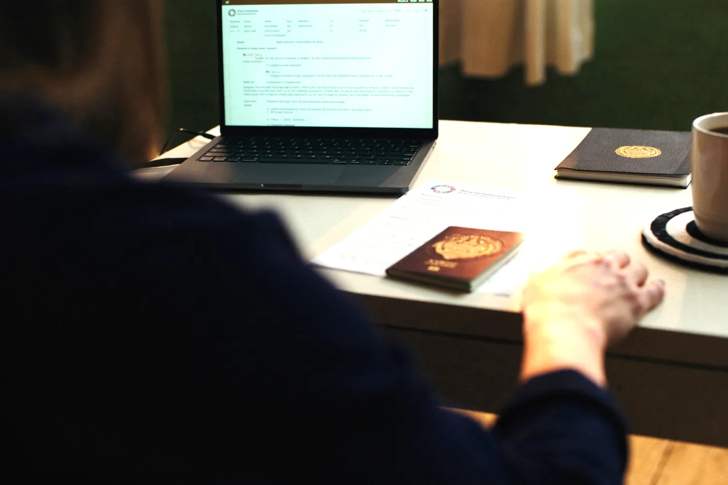 A student's application paperwork, passport and laptop on a desk